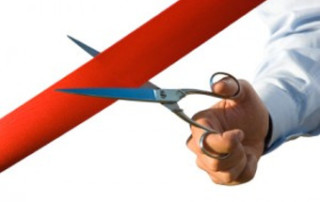 hand holding scissors cutting red ribbon