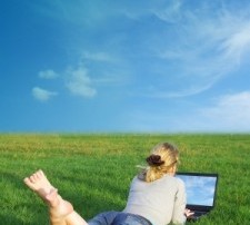 Woman In Open Grassy Field On A Laptop Learning