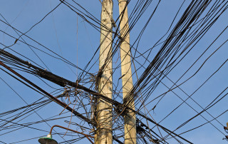 Rat's nest of telephone and electric wires tangled and criss crossed.