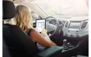 Woman sitting in car looking at tablet