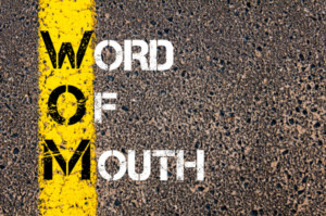Acronym WOM as Word Of Mouth-- yellow paint line on the road against asphalt background. Conceptual image
