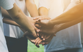 4 people in a circle hands in center - group effort