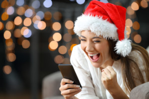 Excited woman reading text on a phone on christmas