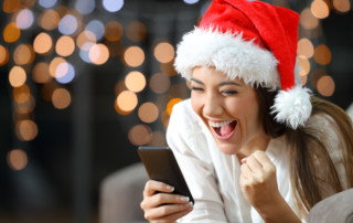 Excited woman reading text on a phone on christmas