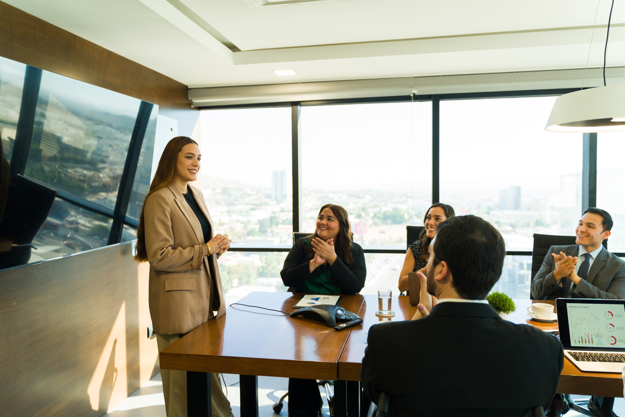Caucasian businesswoman getting recognized for her work with some applause from her colleagues in a meeting room