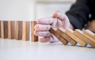Risk and Strategy in Business, Image of hand stopping falling collapse wooden block dominoes effect from continuous toppled block, prevention and development to stability.