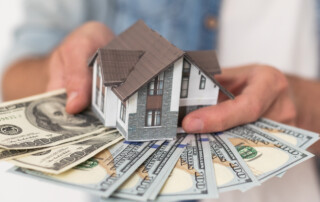 Real estate price and construction concept. Girl weighs money and a toy house in her hands. High quality photo