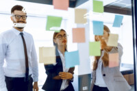 Group of businesspeople teaming up at whiteboard during strategic session in bright modern office