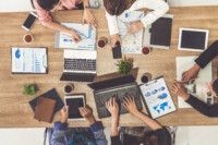 Top view of businessman executive in group meeting with other businessmen and businesswomen in modern office with laptop computer, coffee and document on table. People corporate business team concept.
