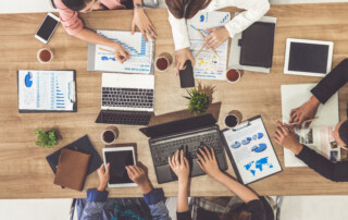 Top view of businessman executive in group meeting with other businessmen and businesswomen in modern office with laptop computer, coffee and document on table. People corporate business team concept.